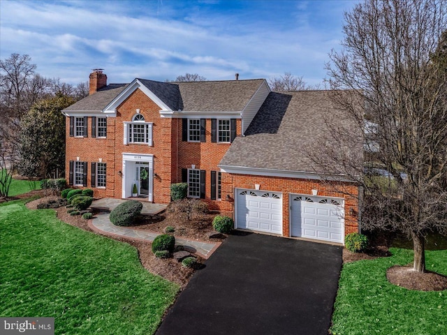 colonial-style house featuring a garage and a front yard