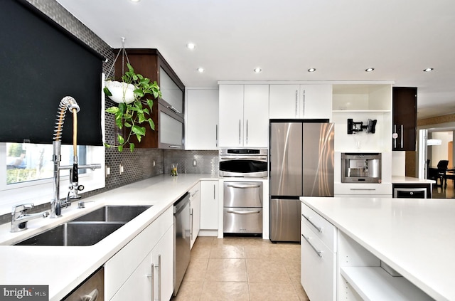 kitchen with backsplash, appliances with stainless steel finishes, light tile patterned floors, and white cabinets