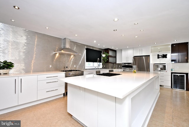 kitchen featuring a spacious island, stainless steel appliances, decorative backsplash, and wall chimney range hood