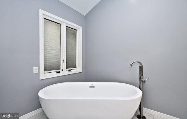 bathroom featuring vaulted ceiling and a tub to relax in