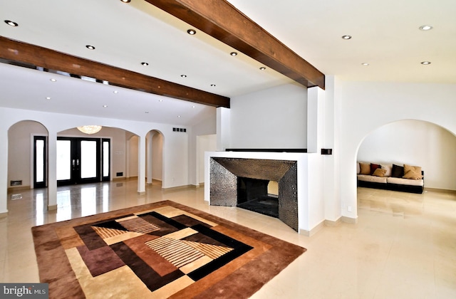 unfurnished living room with beam ceiling and french doors