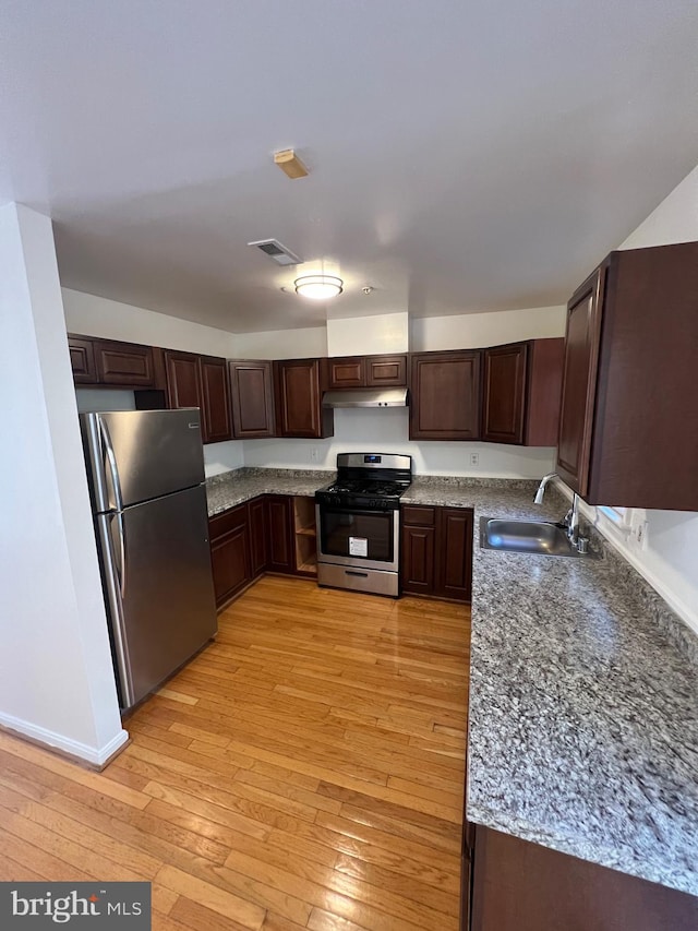 kitchen featuring sink, appliances with stainless steel finishes, dark brown cabinets, and light wood-type flooring