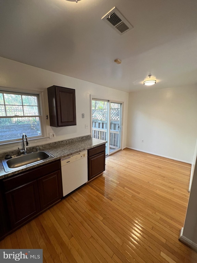 kitchen featuring white dishwasher, sink, dark brown cabinetry, and light wood-type flooring