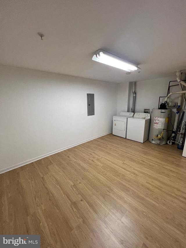 laundry room featuring water heater, electric panel, washing machine and clothes dryer, and light wood-type flooring