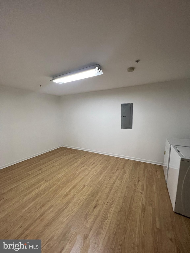 spare room featuring washer and dryer, electric panel, and light hardwood / wood-style flooring