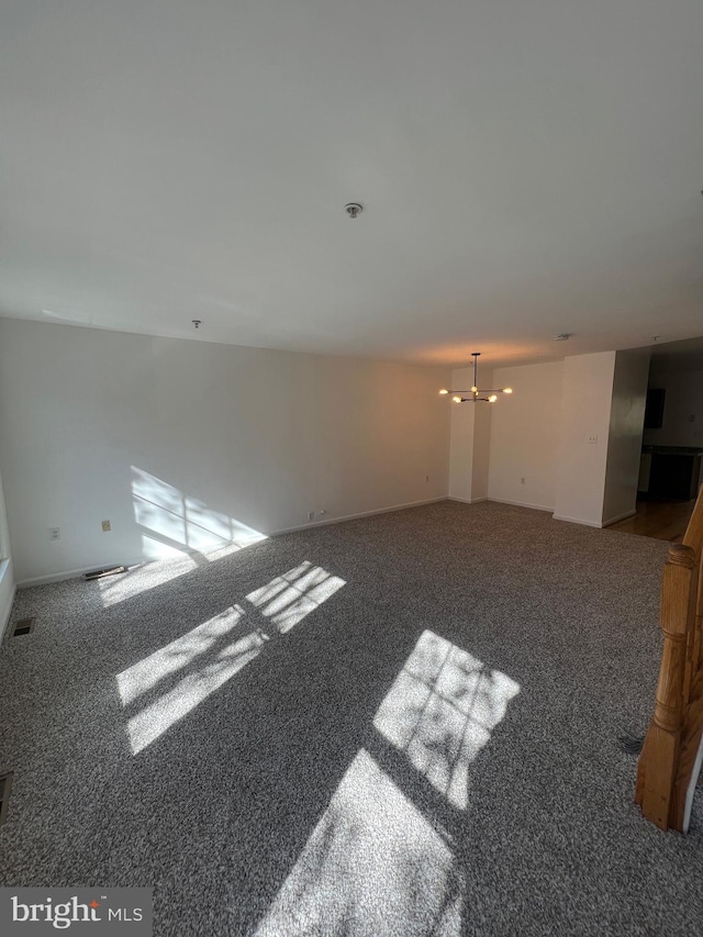 unfurnished living room with carpet flooring and a notable chandelier