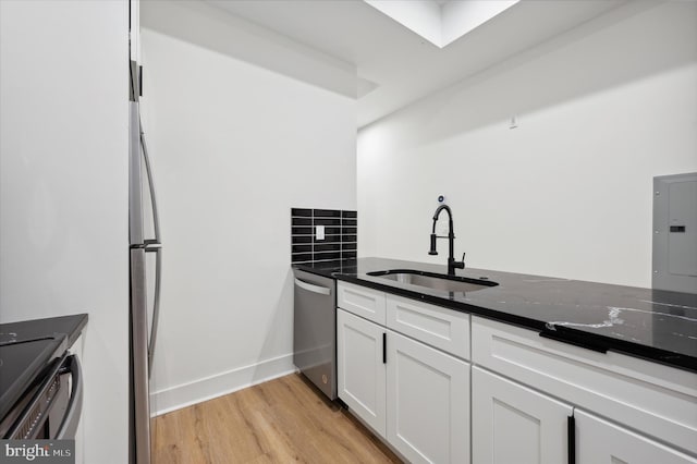 kitchen featuring dark stone counters, electric panel, stainless steel dishwasher, white cabinets, and sink