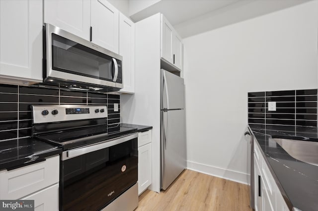 kitchen with light wood-type flooring, stainless steel appliances, decorative backsplash, and white cabinets