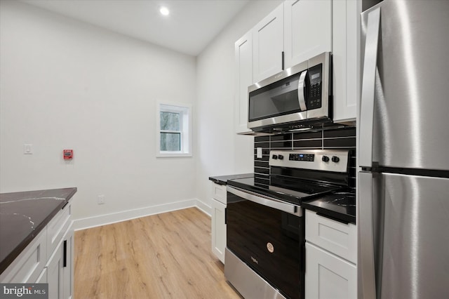 kitchen with backsplash, light hardwood / wood-style flooring, stainless steel appliances, white cabinets, and dark stone counters