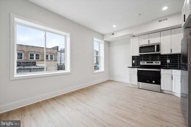 kitchen featuring appliances with stainless steel finishes, decorative backsplash, and white cabinetry