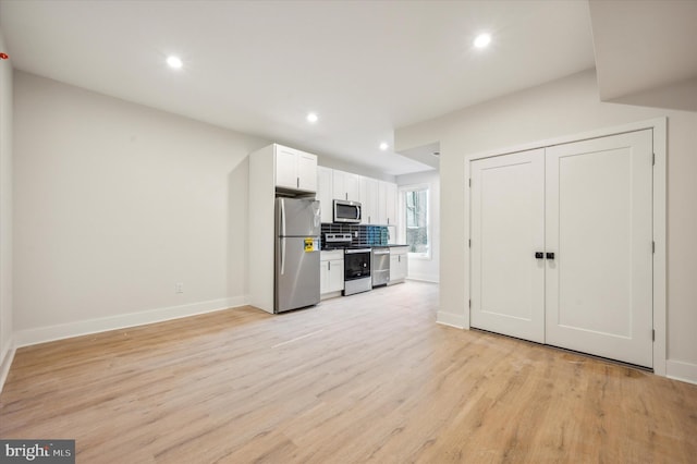 kitchen featuring light wood-type flooring, appliances with stainless steel finishes, backsplash, and white cabinets