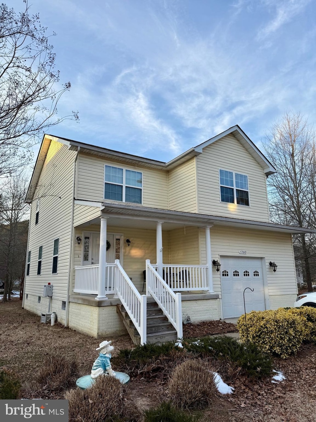 view of front facade featuring a garage, a porch, and central AC unit