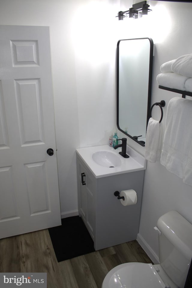 bathroom featuring toilet, vanity, and hardwood / wood-style floors