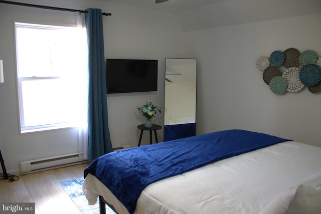 bedroom featuring light wood-type flooring, baseboard heating, lofted ceiling, and ceiling fan