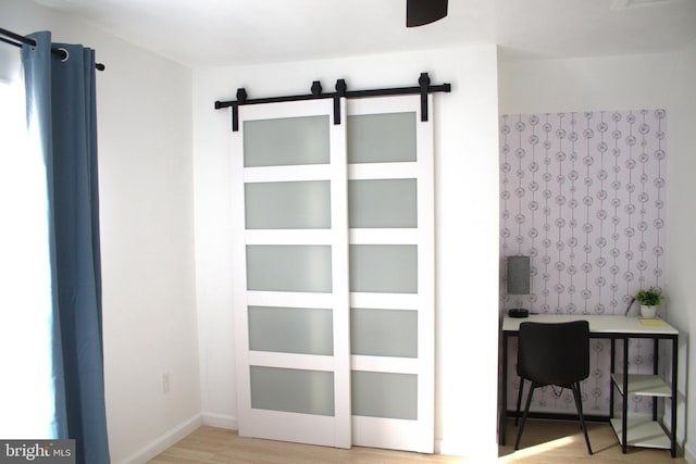 office featuring a barn door and wood-type flooring