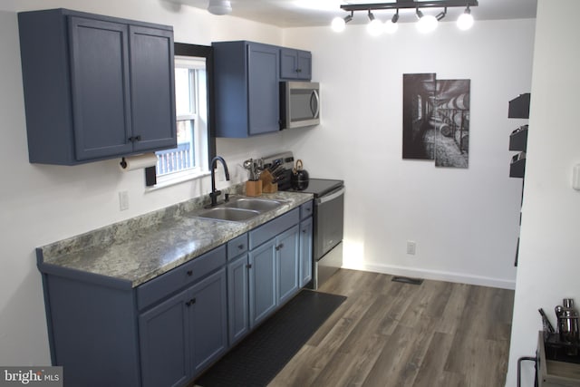 kitchen featuring appliances with stainless steel finishes, blue cabinets, dark hardwood / wood-style floors, and sink