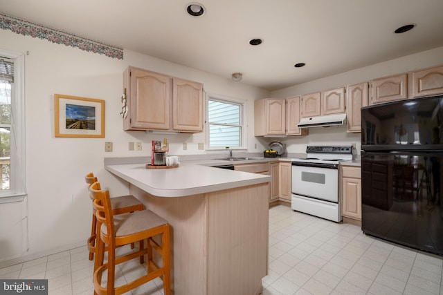 kitchen featuring black refrigerator, light brown cabinets, kitchen peninsula, a breakfast bar, and electric range