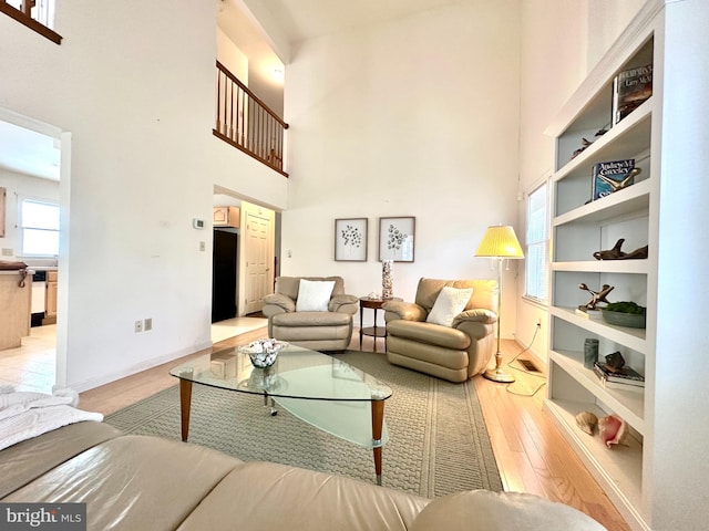 living room featuring a towering ceiling, light hardwood / wood-style floors, and built in features