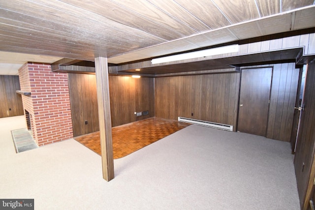 basement featuring wooden walls, a baseboard radiator, and carpet flooring