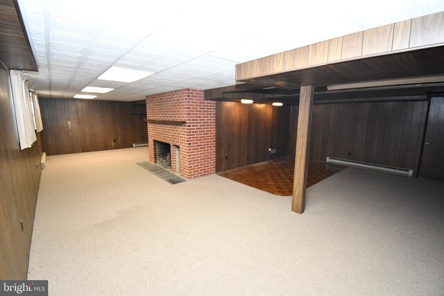 basement with a baseboard heating unit, light carpet, a fireplace, and wood walls