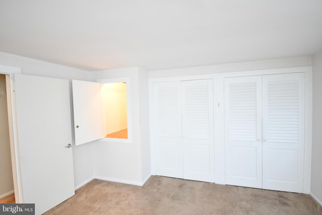 unfurnished bedroom with light colored carpet and multiple closets