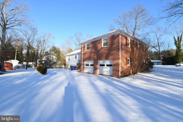 view of snowy exterior featuring a garage