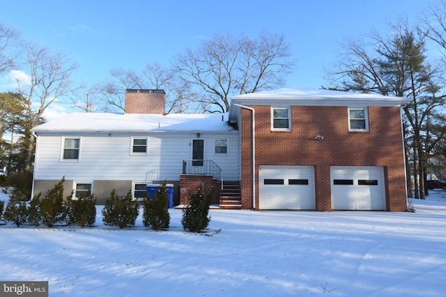 snow covered rear of property featuring a garage