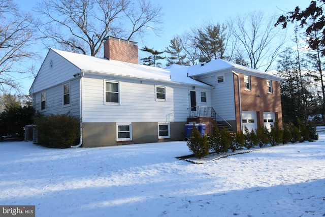 snow covered back of property with a garage