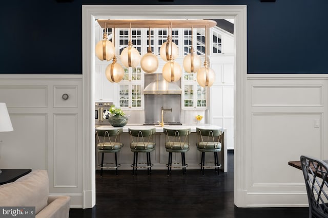 bar with extractor fan, oven, and white cabinetry