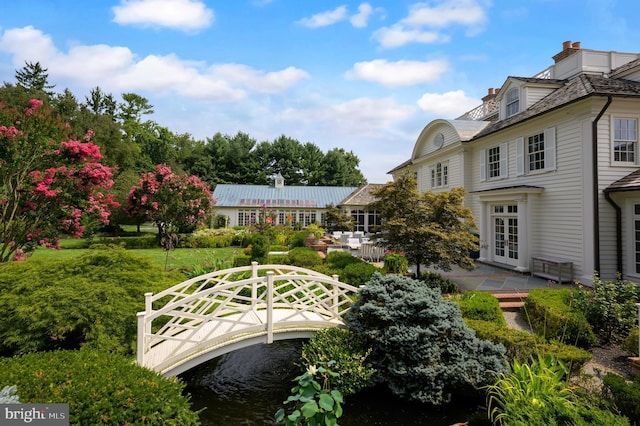 rear view of property with a water view, french doors, and a yard