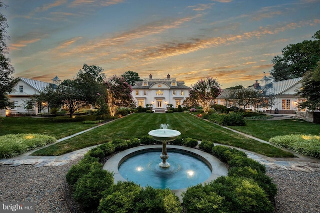 pool at dusk featuring a lawn