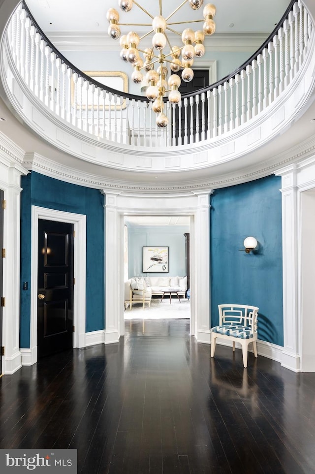 foyer entrance featuring hardwood / wood-style flooring, a high ceiling, ornamental molding, and ornate columns