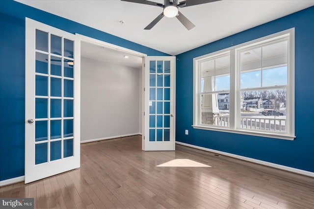 spare room featuring wood-type flooring, ceiling fan, and french doors