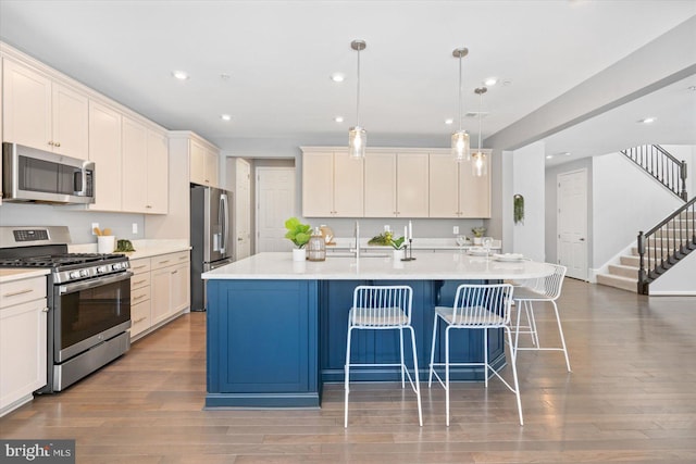 kitchen with a kitchen island with sink, hanging light fixtures, and stainless steel appliances