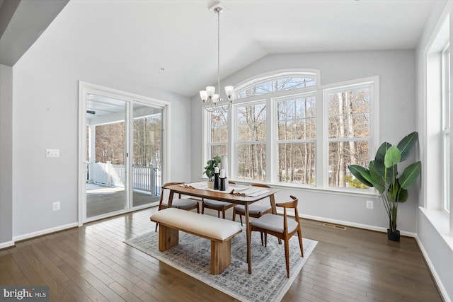 dining area featuring vaulted ceiling, a healthy amount of sunlight, a notable chandelier, and dark hardwood / wood-style flooring