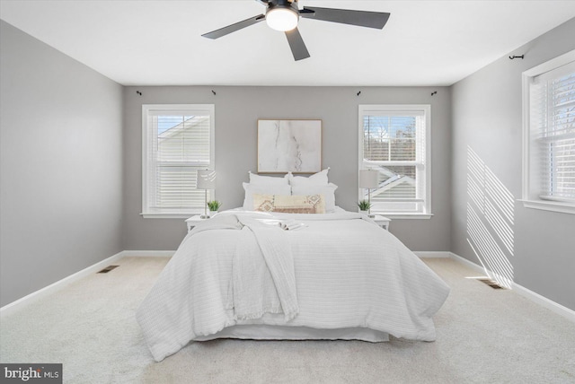 bedroom featuring multiple windows, ceiling fan, and light carpet