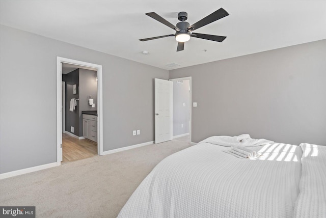 bedroom with light carpet, ceiling fan, and ensuite bath