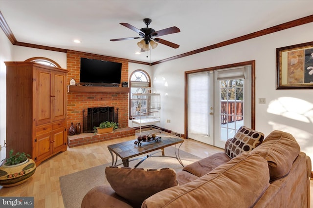 living room with ceiling fan, a fireplace, ornamental molding, light hardwood / wood-style floors, and french doors