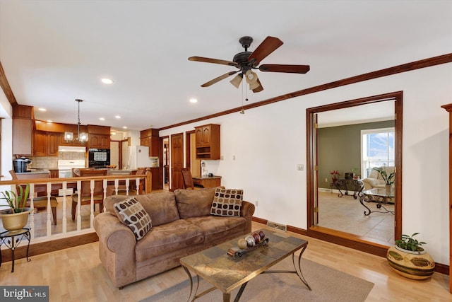 living room featuring crown molding, light hardwood / wood-style flooring, and ceiling fan