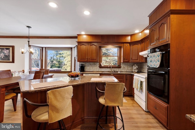 kitchen featuring sink, ornamental molding, white electric stove, a kitchen island, and pendant lighting