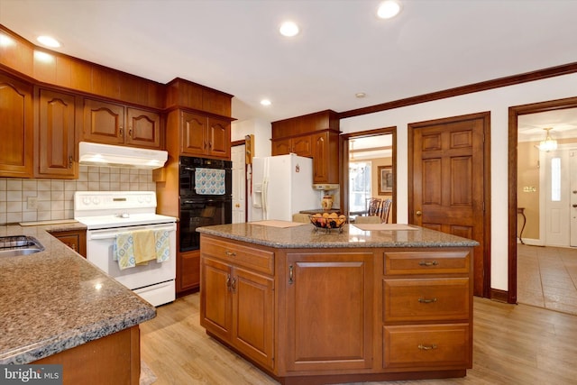 kitchen with tasteful backsplash, white appliances, light stone countertops, and a kitchen island