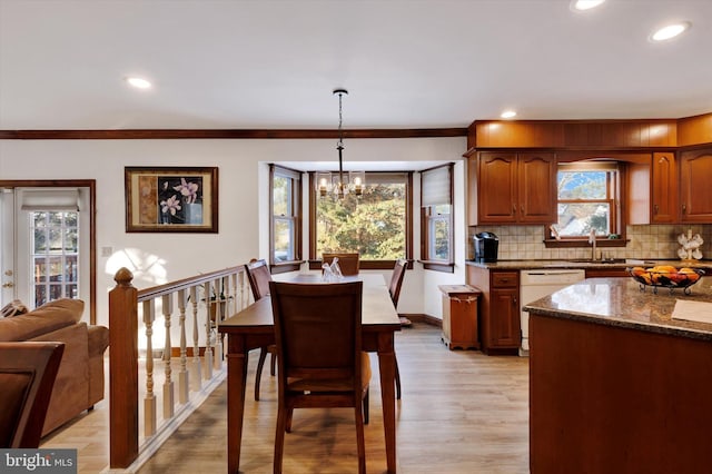 kitchen featuring decorative light fixtures, dark stone countertops, backsplash, ornamental molding, and white dishwasher