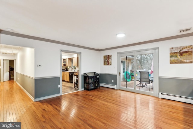 interior space featuring a baseboard heating unit, crown molding, and wood-type flooring