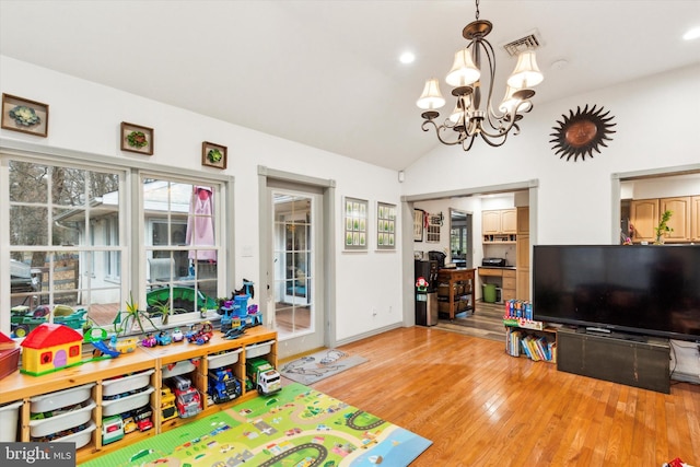 rec room with lofted ceiling, hardwood / wood-style flooring, and a notable chandelier