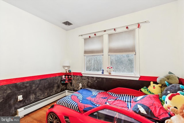 bedroom featuring hardwood / wood-style floors and a baseboard heating unit