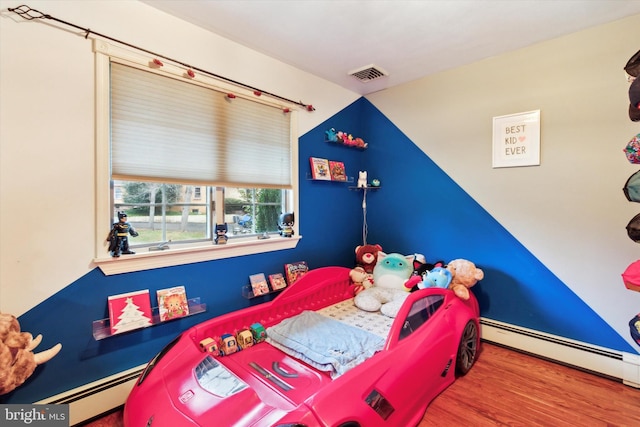 bedroom featuring a baseboard heating unit and hardwood / wood-style floors