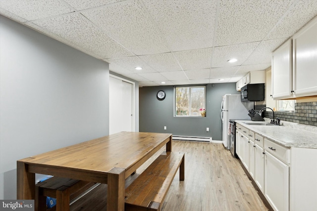 kitchen with white cabinets, a paneled ceiling, tasteful backsplash, light hardwood / wood-style floors, and sink