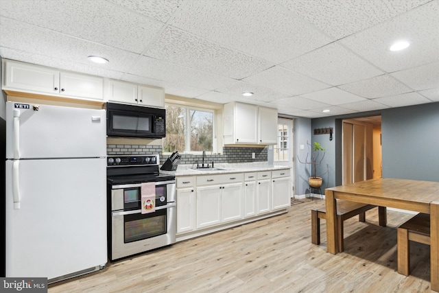 kitchen featuring double oven range, a paneled ceiling, white refrigerator, and white cabinets