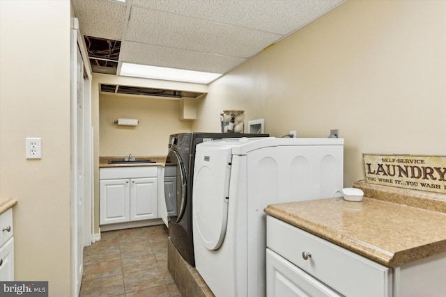 laundry area with cabinets, washing machine and clothes dryer, and sink