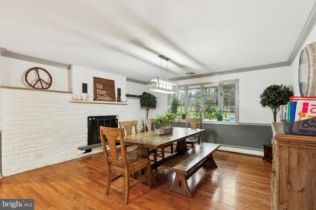 dining space with a fireplace, a baseboard radiator, and hardwood / wood-style flooring